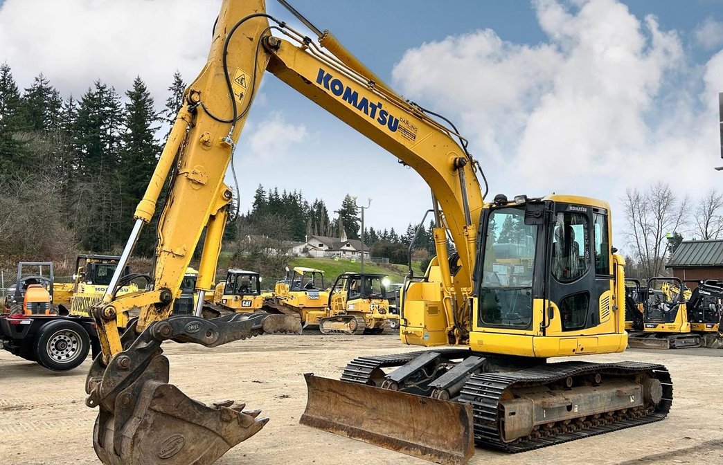 Excavator with hydraulic breaker breaking concrete urban street