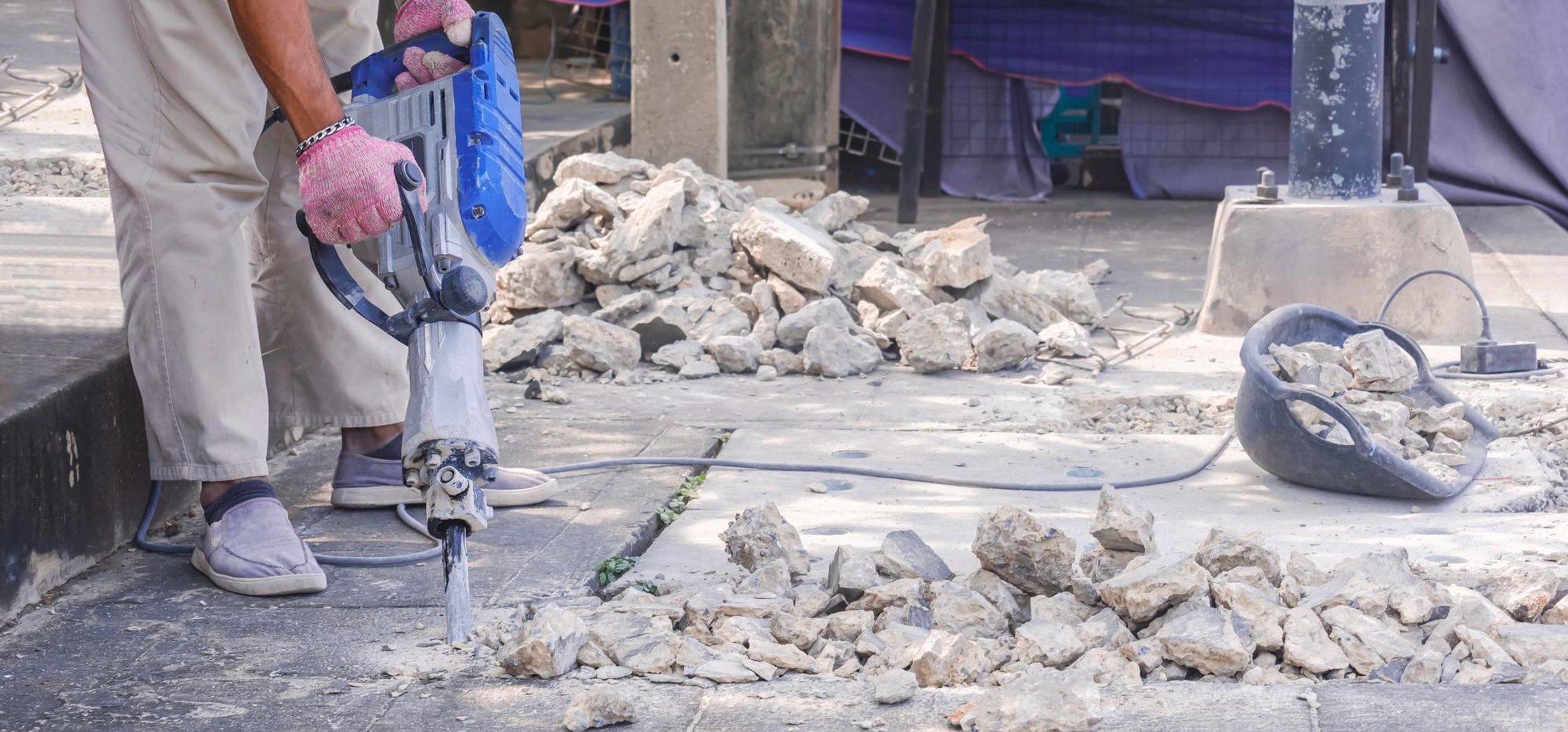 Excavator clearing concrete rubble at urban demolition site