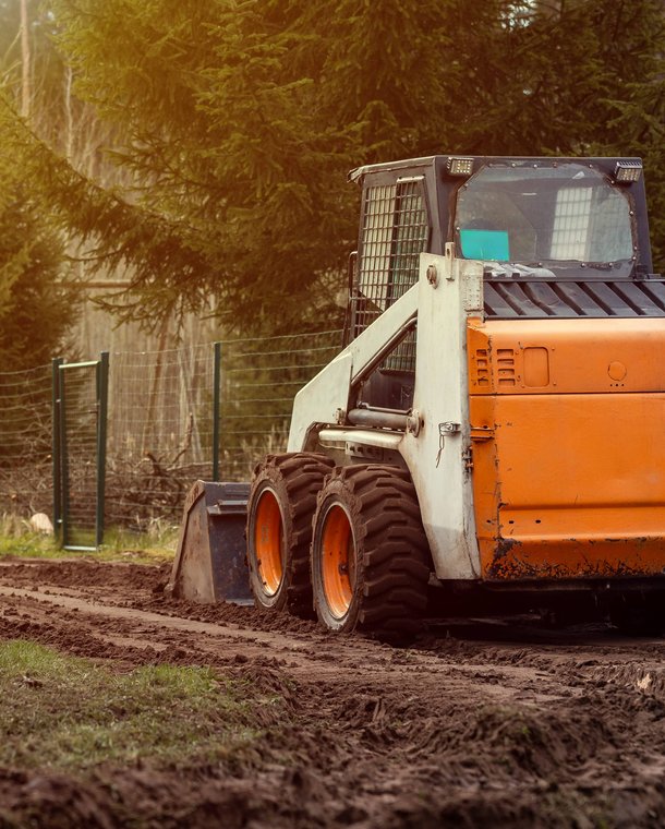 Bobcat skid steer grading dirt in residential backyard