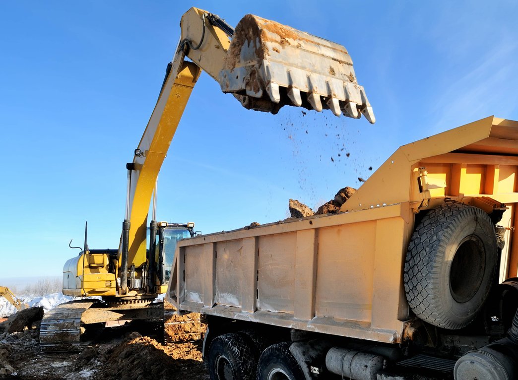 Excavator dumping material into haul truck at site